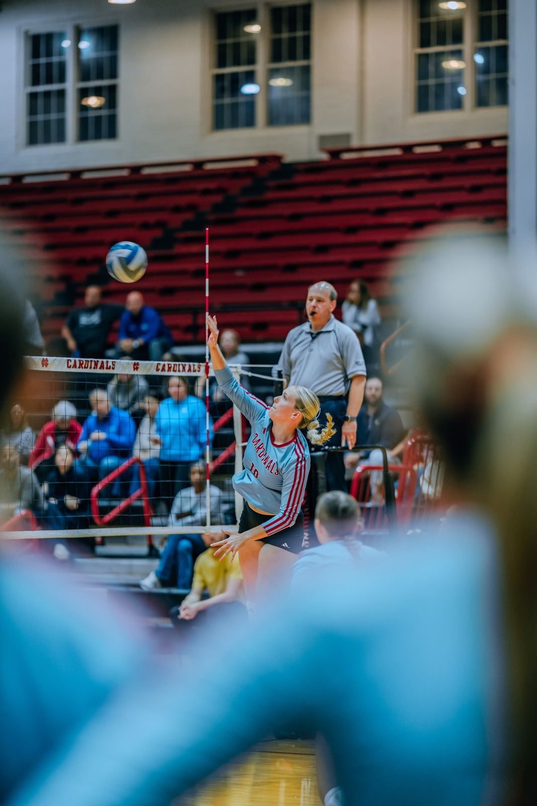 A player in a gray uniform reaches overhead for the ball.
