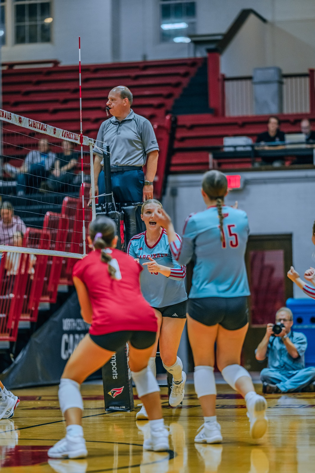 A player in a light blue uniform points forward while a player in red crouches.