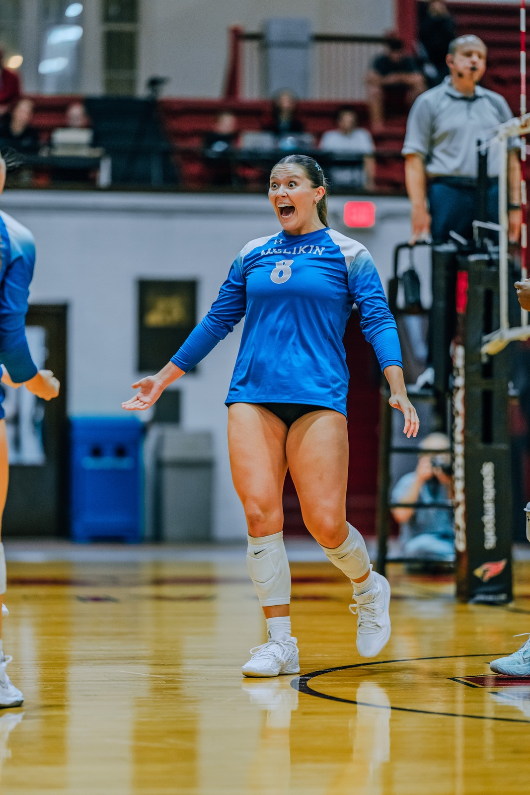 A Millikin player in a blue uniform with arms outstretched and mouth open.
