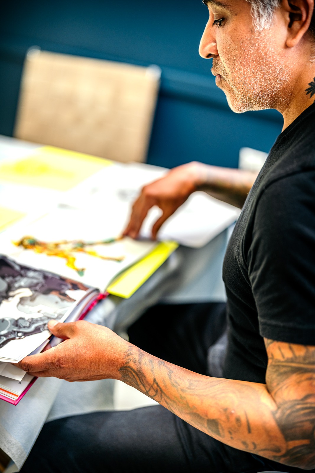 A person in a black shirt looks down at an open book.