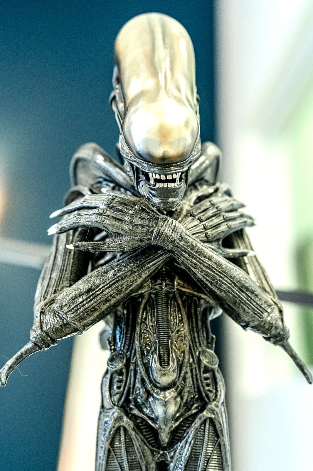 A metallic alien figurine stands with its arms crossed.