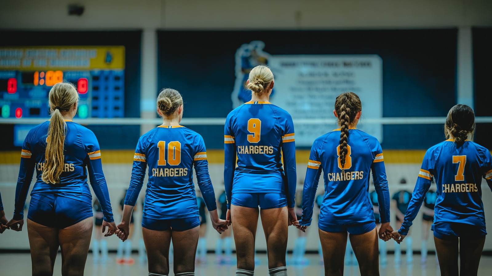 Five players in blue uniforms stand holding hands.