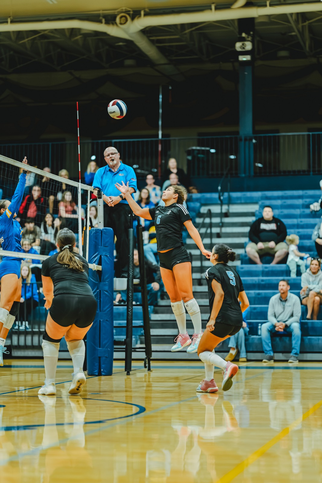 A player in black jumps for the ball while another player in black crouches.
