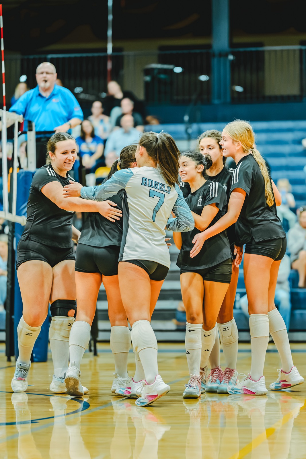 Players in black and white uniforms hug on a court.