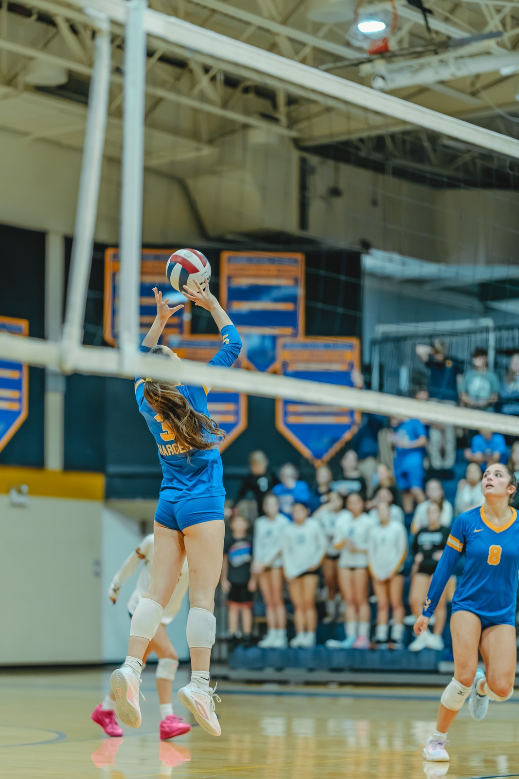 A player in blue jumps and reaches for the ball.