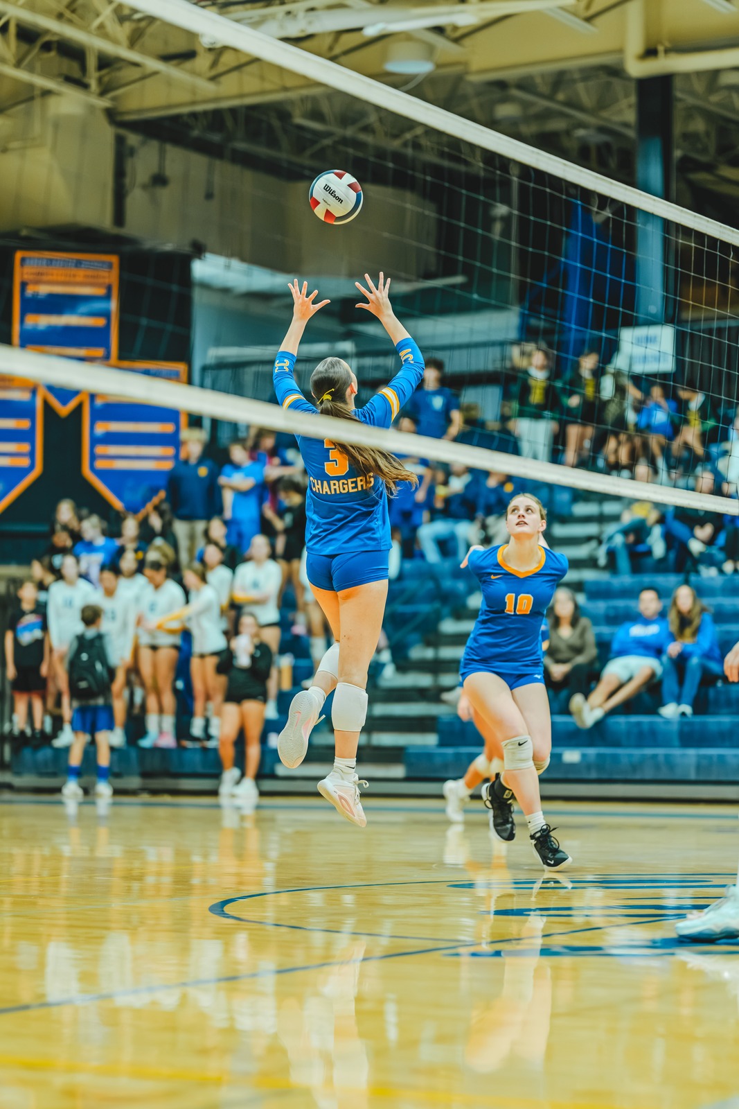 A player in blue jumps with arms extended toward the ball.