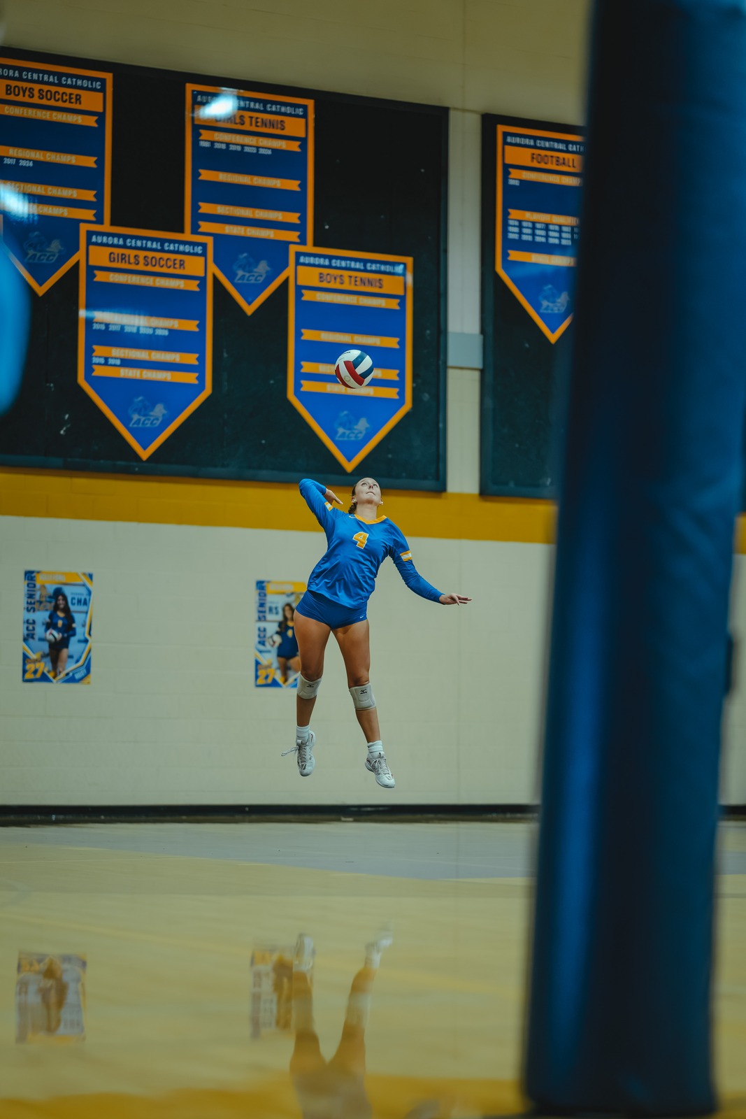 A player in a blue uniform jumps and swings her arm at the ball.
