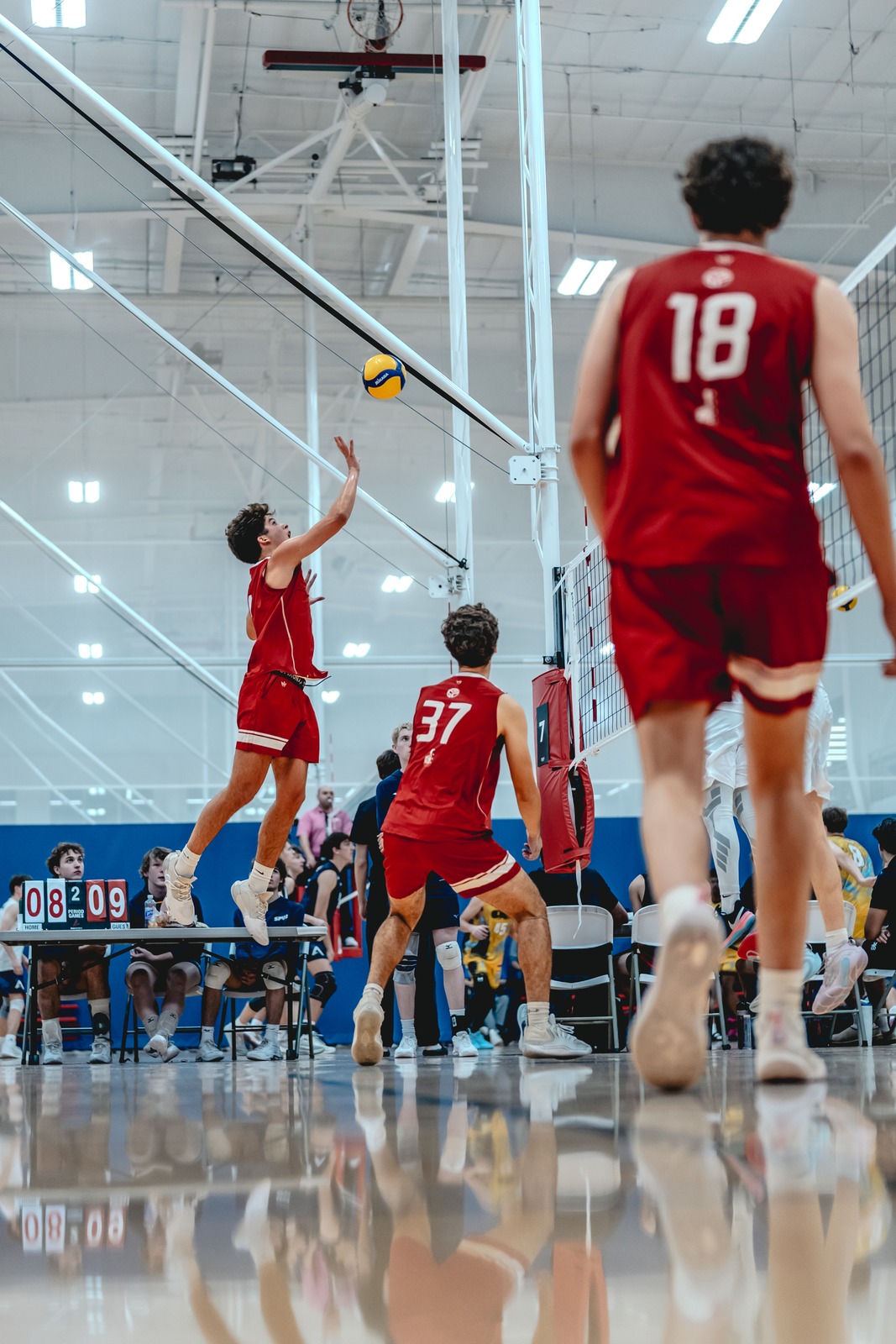 A player in red reaches overhead for the ball.